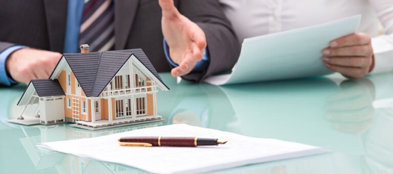 Real Estate Jobs professional discussing property documents with a client beside a model house during a real estate consultation meeting.