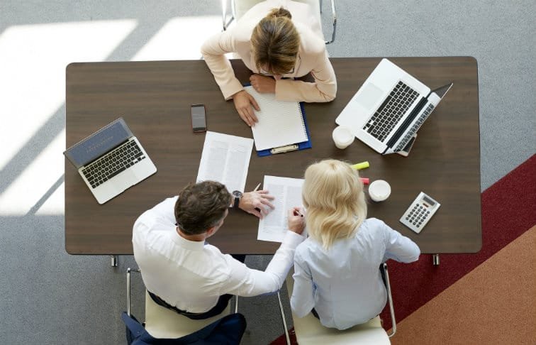 Real estate professionals discussing property deals and career opportunities in an office meeting